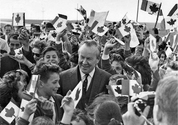 Prime Minister Lester B. Pearson in a crowd of Canadians holding Canadian flags 
