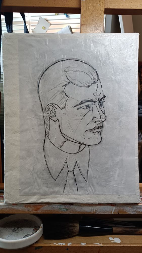 an image of a piece of paper with the head of a man drawn on it pasted to a gessoed canvas. 