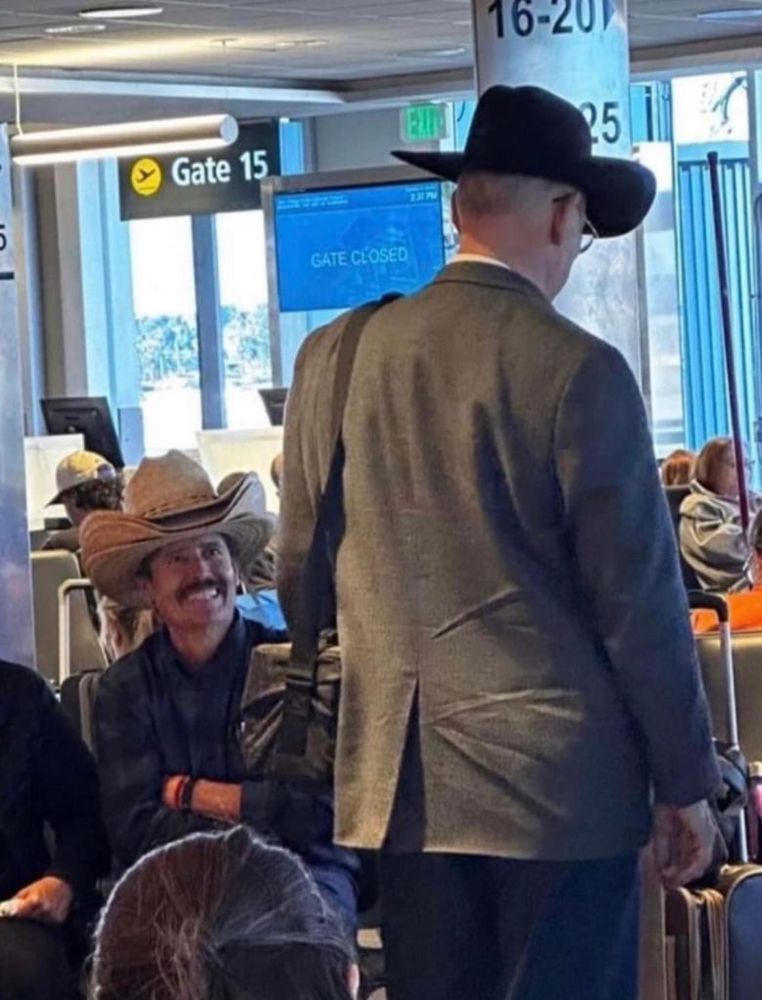 A man with many hats laughs at a lower quality single hat man