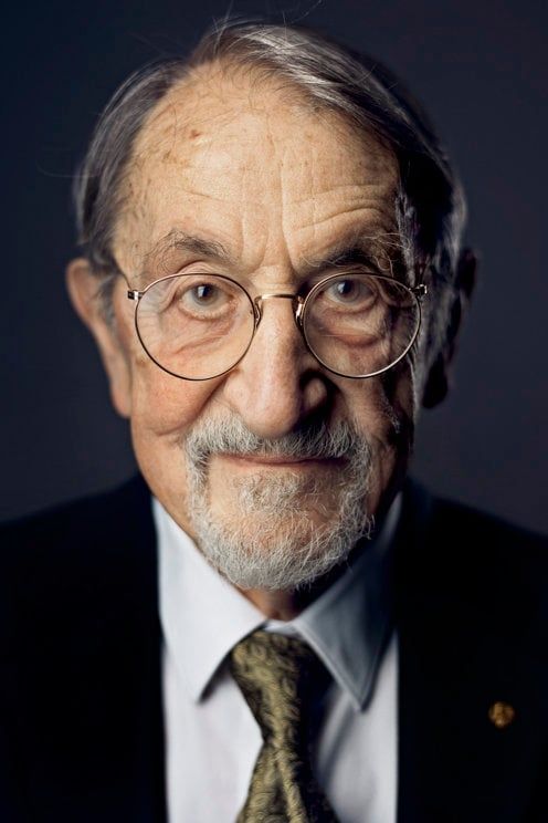 Portrait of Martin Karplus, old elegant man with eyeglasses staring at the camera.
