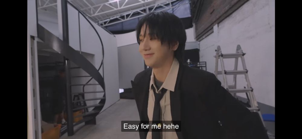 Screenshot of Yesung from his behind the scenes video for the live version of “There she goes again”, saying “easy for me! hehe” while looking down with a shy smile. 