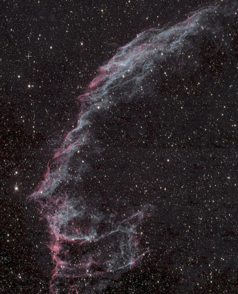 Blue-white wisps of a galactic nebula against the backdrop of countless stars in the summer Milky Way.