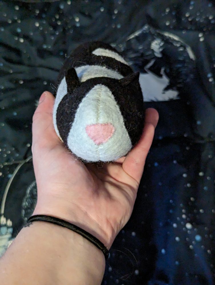 A photo of a black and white guinea pig plush