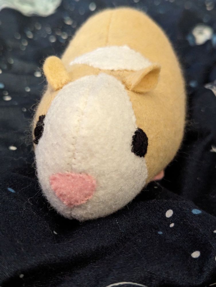 A photo of a tan guinea pig plush with a white face