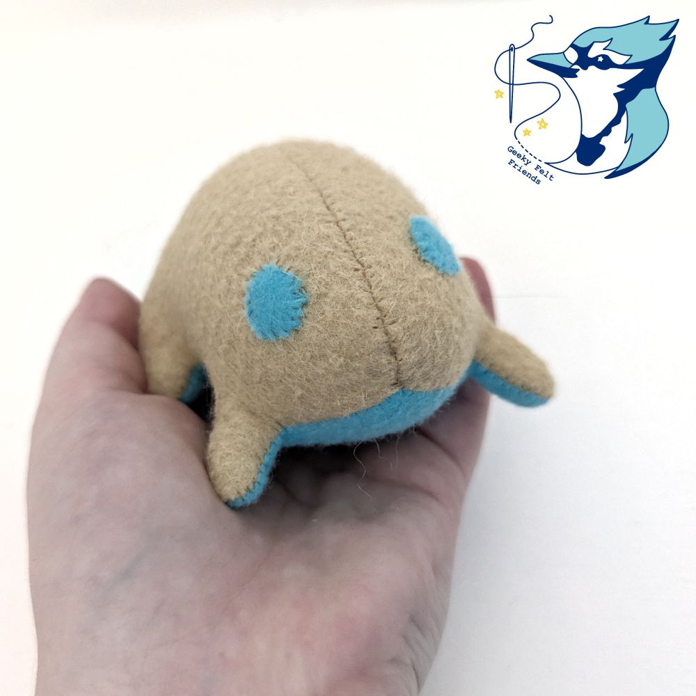 A closer photo of a simple plush frog in tan and light blue