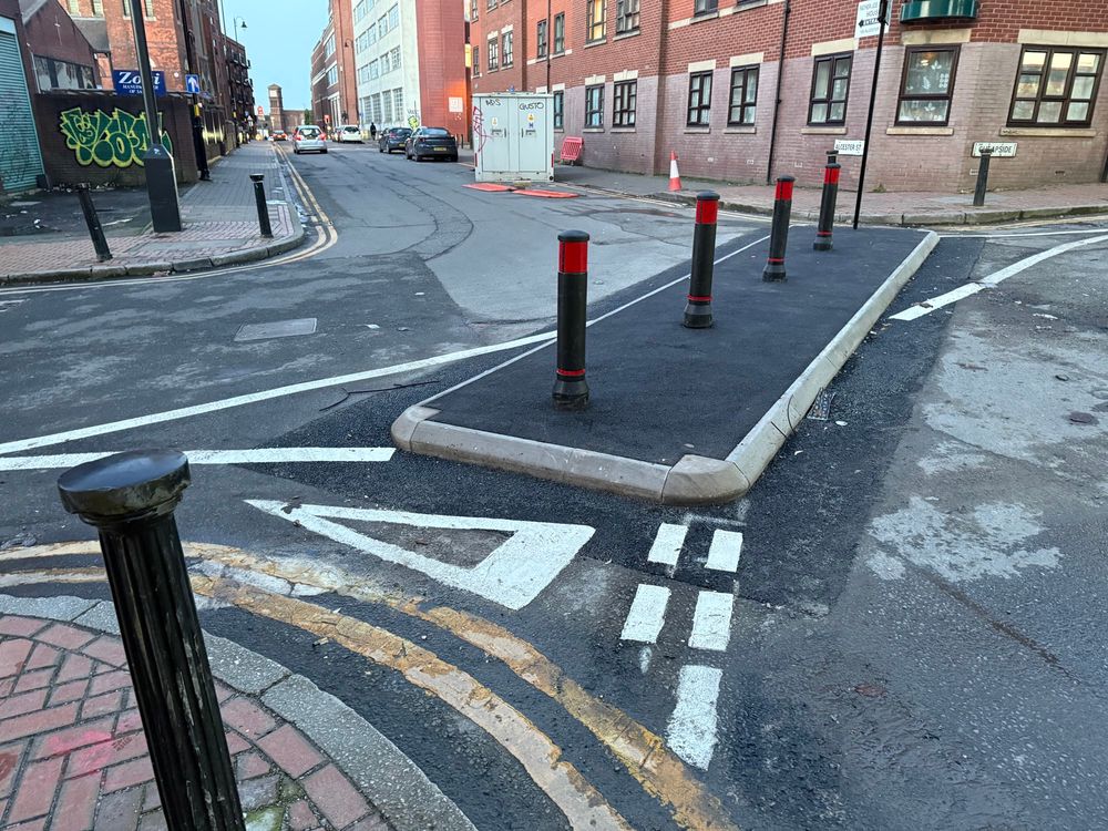 A row of bollards that stop through-traffic from using a crossroads. Cycles can still get through either side of the bollards.