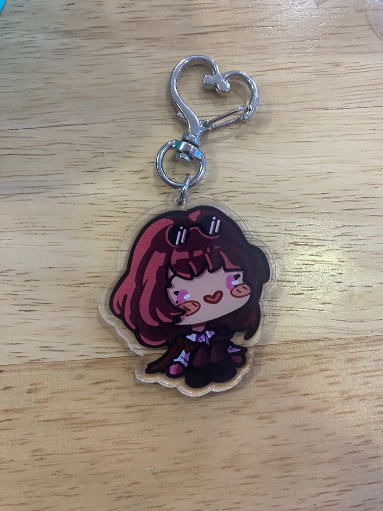 A keychain of Kafka from Honkai Star Rail in chibi style, with a silver heart-shaped chain.