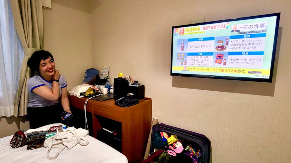 Woman laughing watching TV in a hotel room