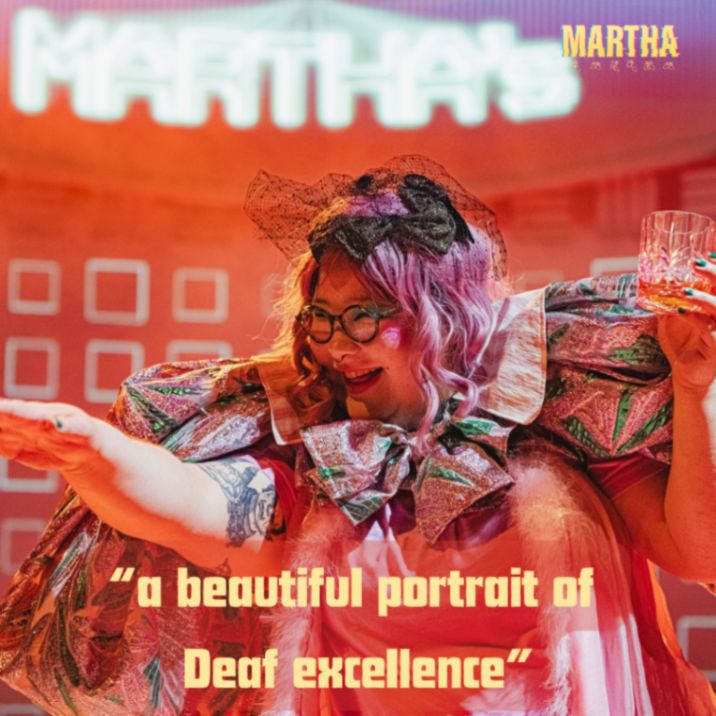 Bea in pink, with oversized sleeves and large glasses smiles broadly and points out of shot. An audience quote " a beautiful portrait of Deaf excellence" in yellow at the bottom