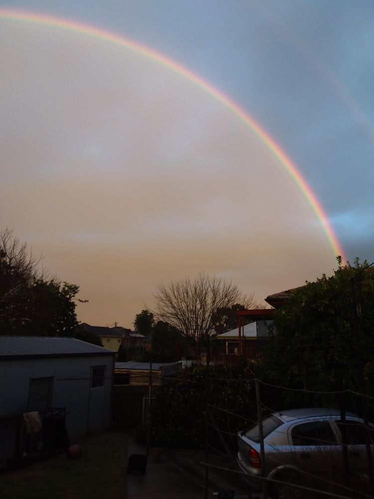 Photo of double rainbow, where the sky in front of the first main rainbow is a lighter colour than the sky behind.