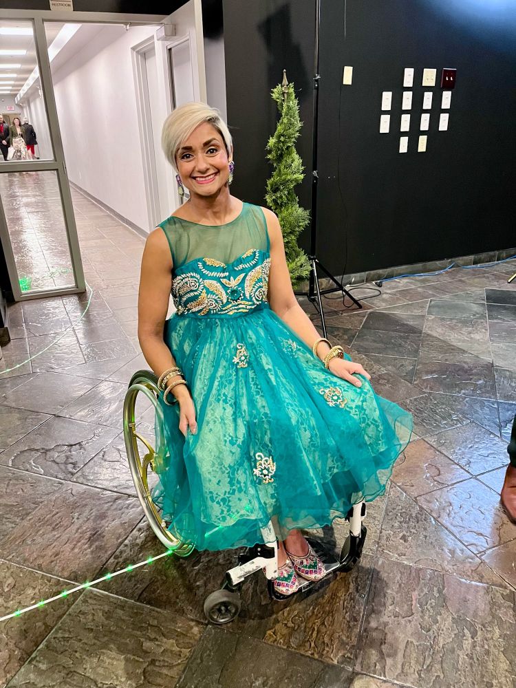 Bean Gill smiling sitting in her chair, looking beautiful and sparkly. 