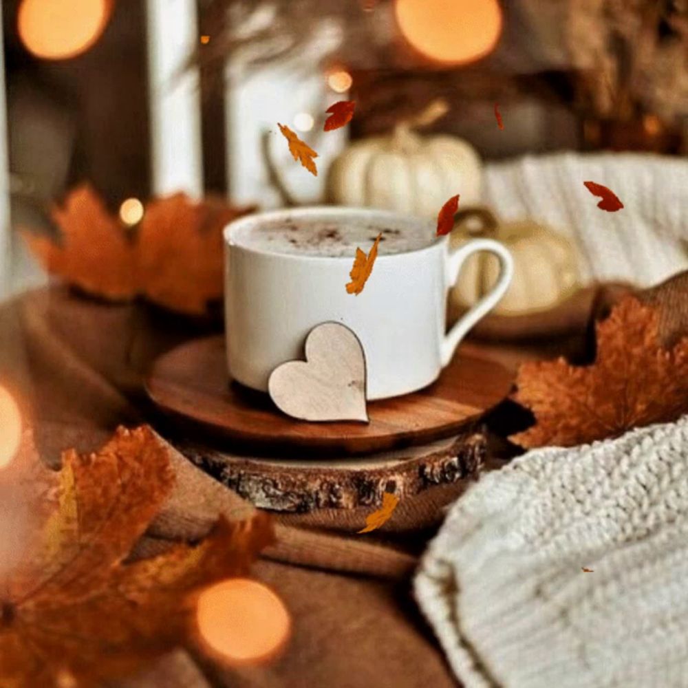 a cup of coffee sits on a wooden saucer with leaves falling around it