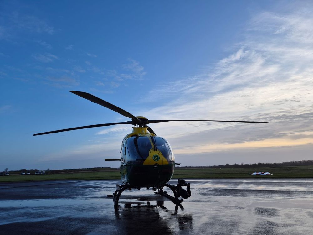Yellow and green helicopter outside the airbase hangar.