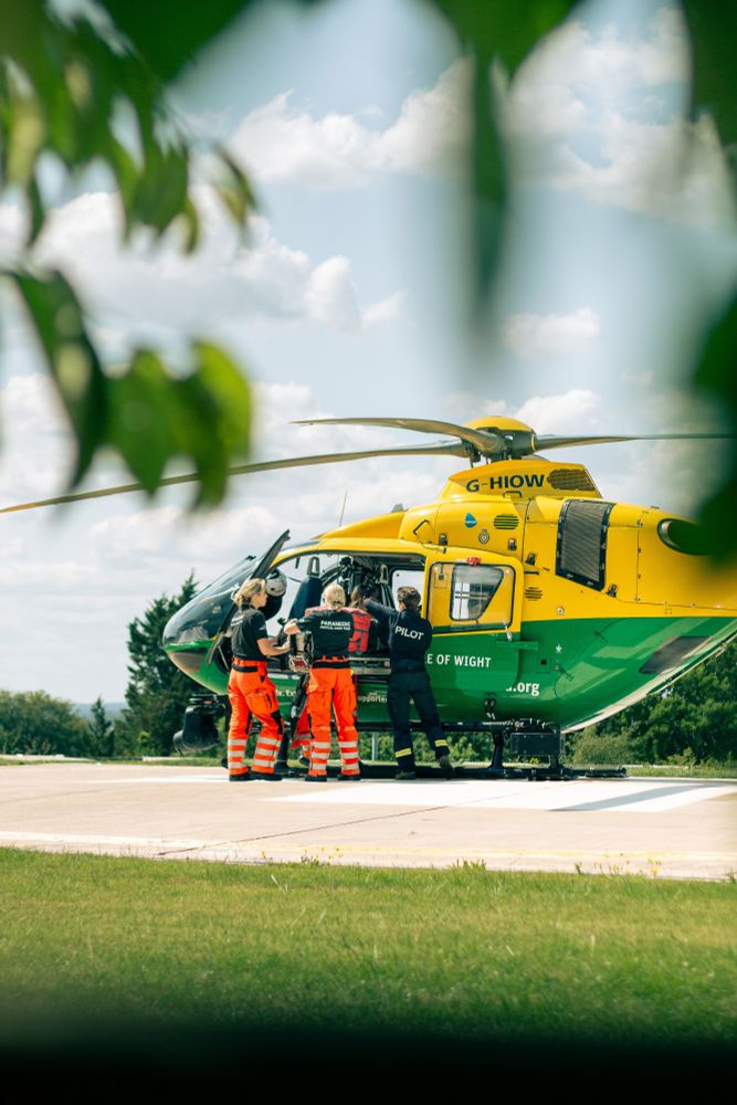 Three crew members packing kit into the helicopter.