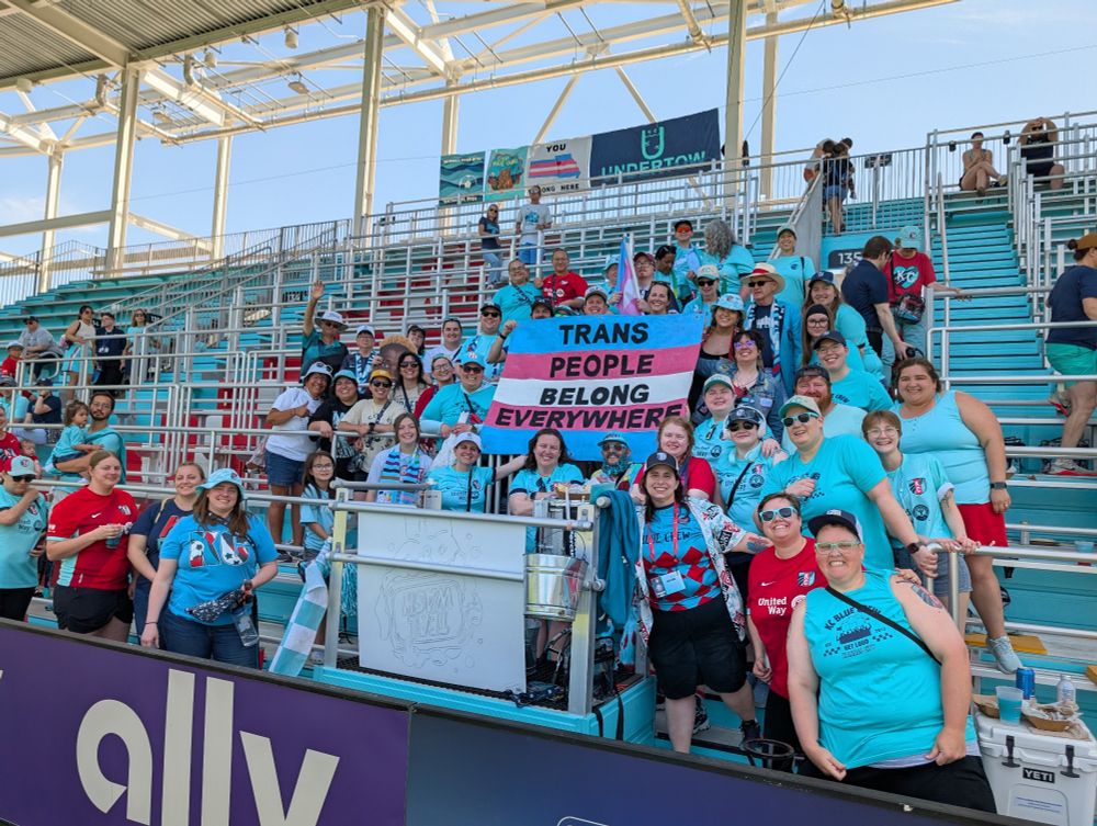 Picture of big group of Blue Crew and Bridge Brigade holding Trans People Belong Everywhere sign
