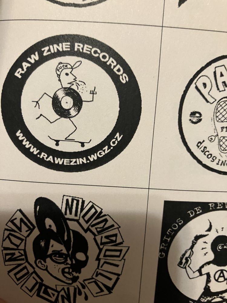 The Raw Zine Records logo, which is a little man whose torso is a record. The little man is flipping you off and spitting while he skateboards. He is wearing a hat that says "FUCK"