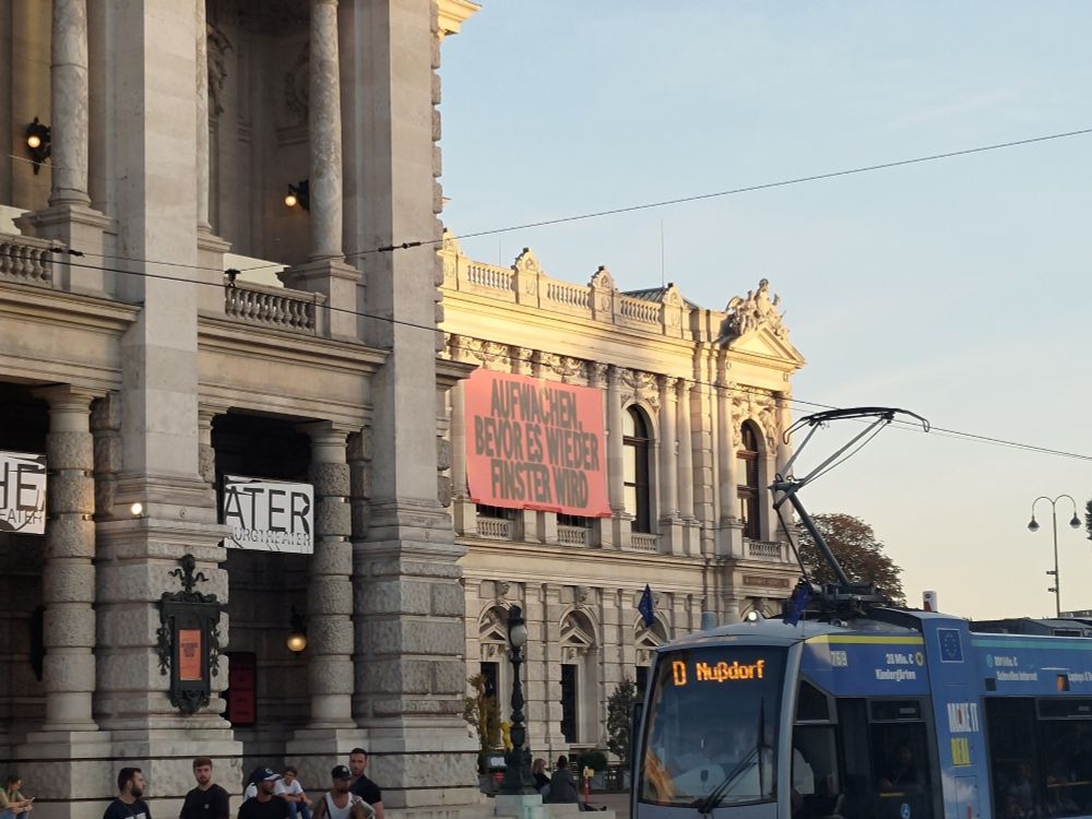 Großes Banner am Burgtheater in Wien mit der Aufschrift "Aufwachen, bevor es wieder finster wird"