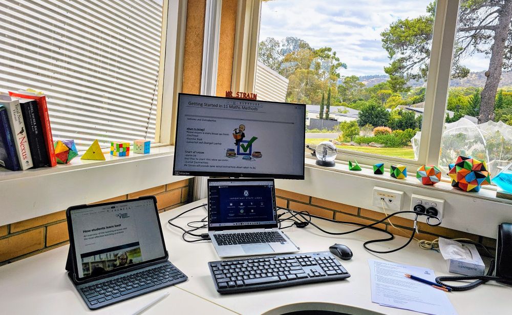 View of desk with pc and ipad and views of window to trees and hills.