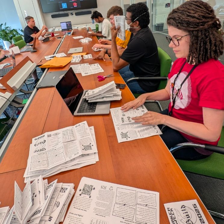 A group of guild members folding and assembling zines at a table