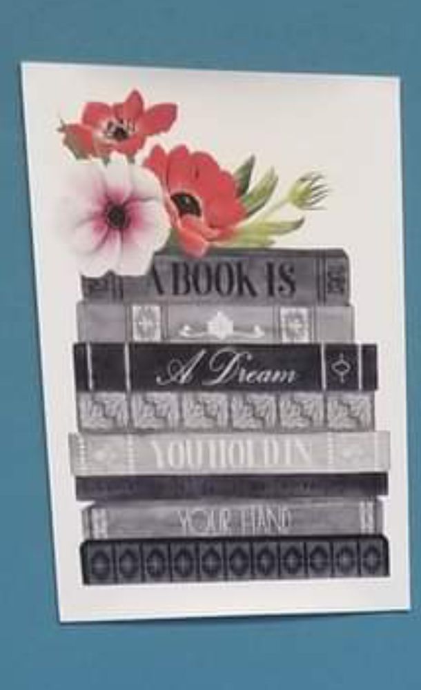 A poster of stacked books and flowers. It reads: a book is a dream you hold in your hand. 