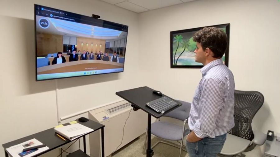 Photo of an informally dressed young man, hands in pockets, looking at a virtual audience. This is MIT's WCC Communication Studio, "a self-service recording and editing space designed to help users sharpen their oral presentation and communication skills."