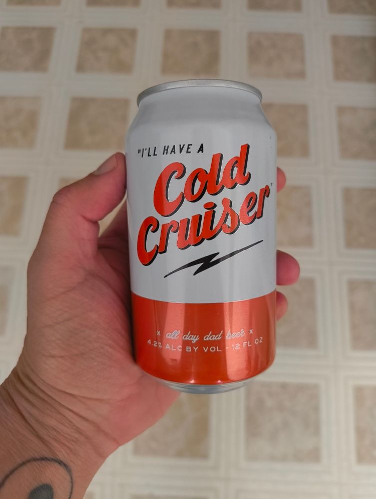 A hand holding a white & red beer can, the copy on the can reads: "I'll have a Cold Cruiser. All Day Dad Beer".