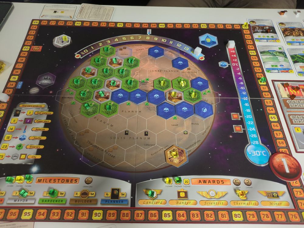 Game board oft Teraforming Mars. The Green player has many forests and cities, while the yellow player only has one City and few forests.