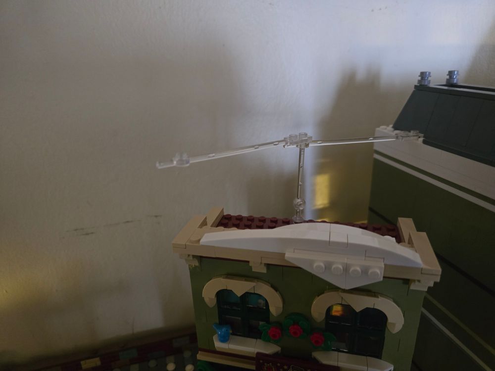 Photo of part of the roof of the museum and the roof of the toy store clear sticks running horizontally are connected to the museum roof & another clear stick that is connected to the toy store roof running vertically is holding them up