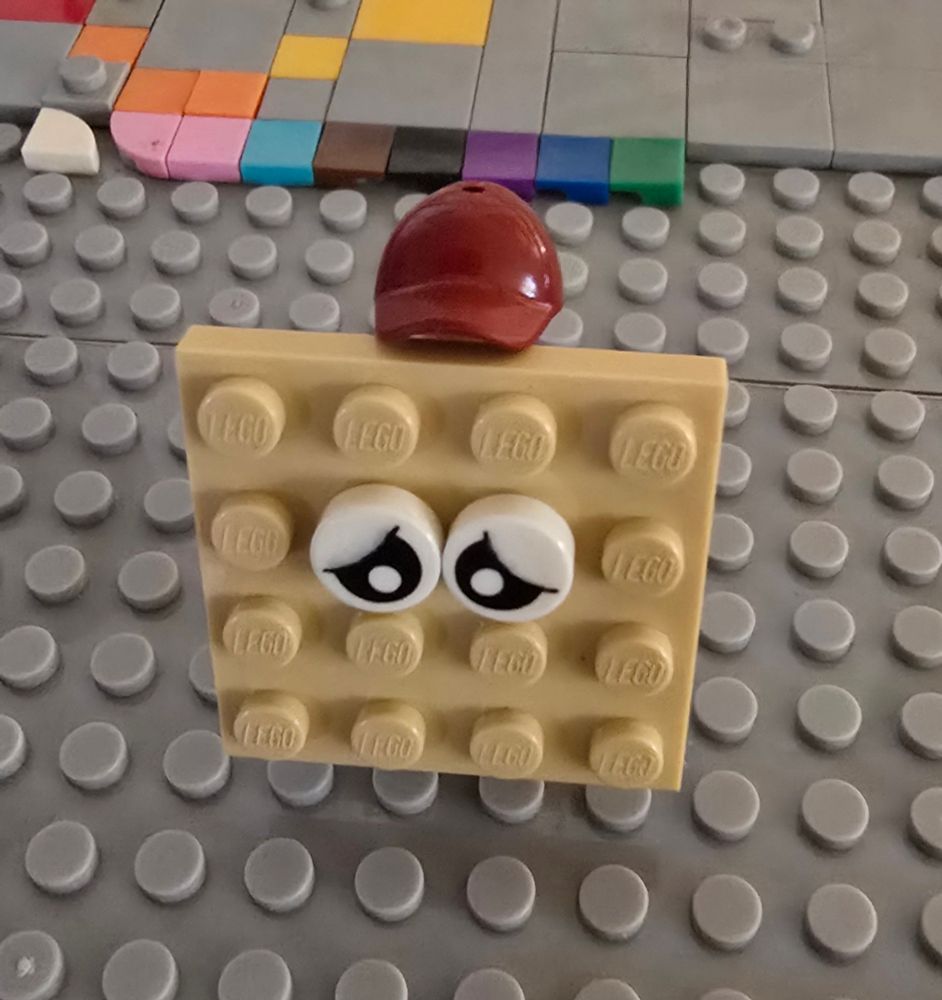 Magat Crackkker represented as a 4x4 tan lego plate w/ sad googly eyes & a red ball cap
