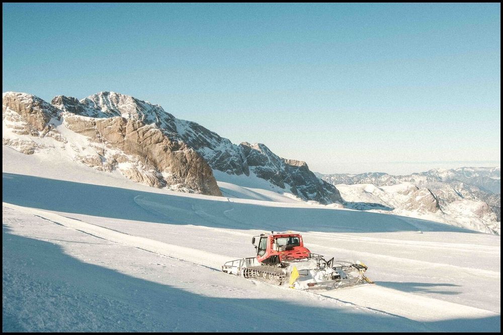  Snowcat with snow blow on a glacier. On the horizont are mountaints