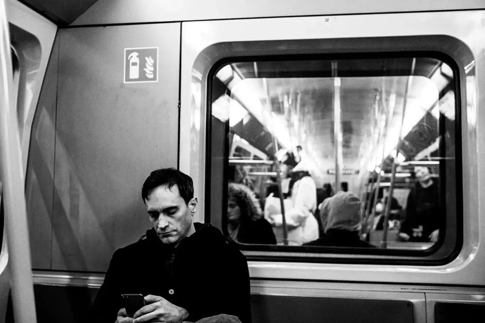 man sitting in the subway starring on his phone