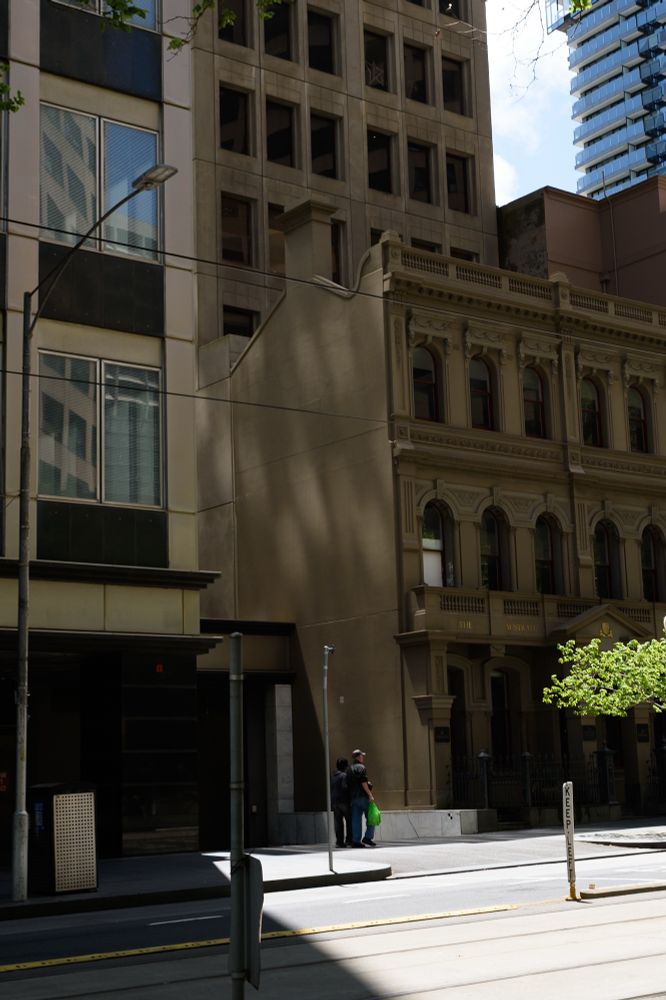 Pedestrians walk through a shaft of light 