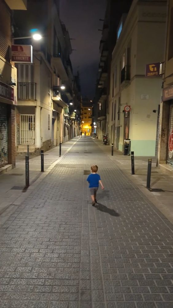 A 3-year-old walking independently down the street followed closely by his parents without concern for car traffic 