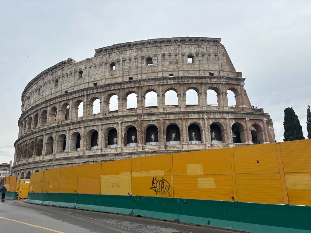 The Colosseum in Rome with yellow hoarding (in fact for a metro extension) around it so it looks like it’s under construction. 
