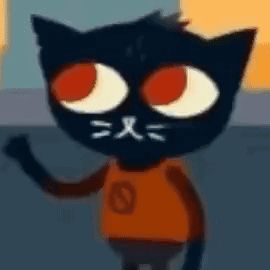 a black cat with red eyes and a white nose is wearing an orange shirt .