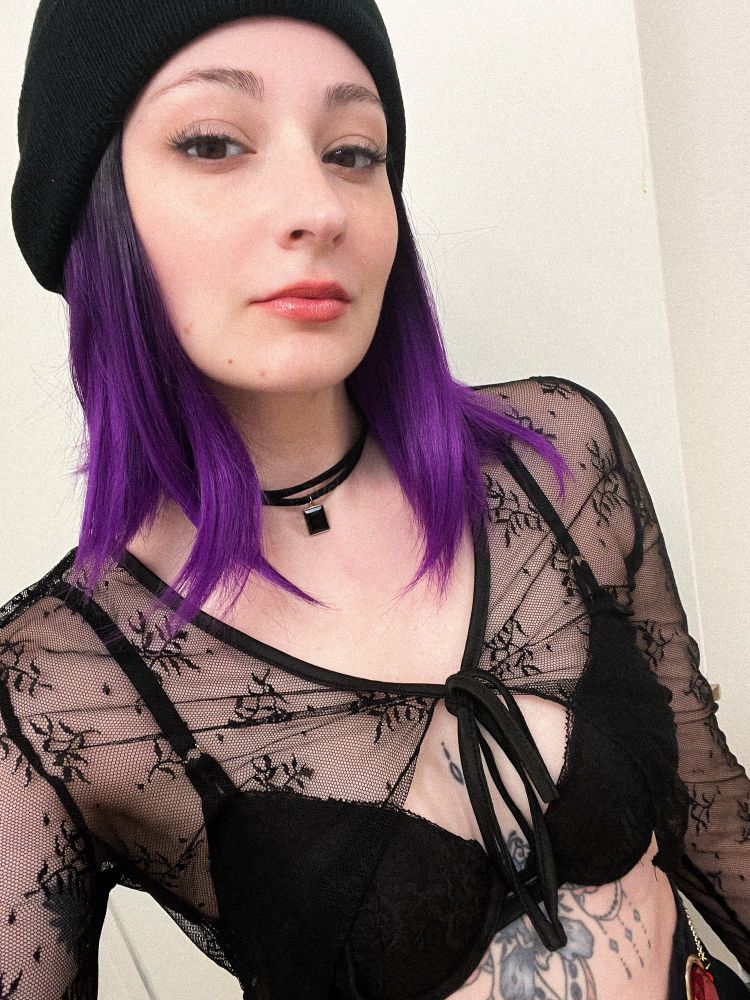 White girl wearing black clothes, black beanie and a purple wig 