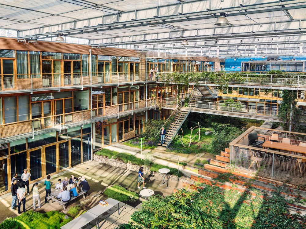 Photo of the inside of a university building at WUR, it looks like a mix of a greenhouse with offices that have balconies.