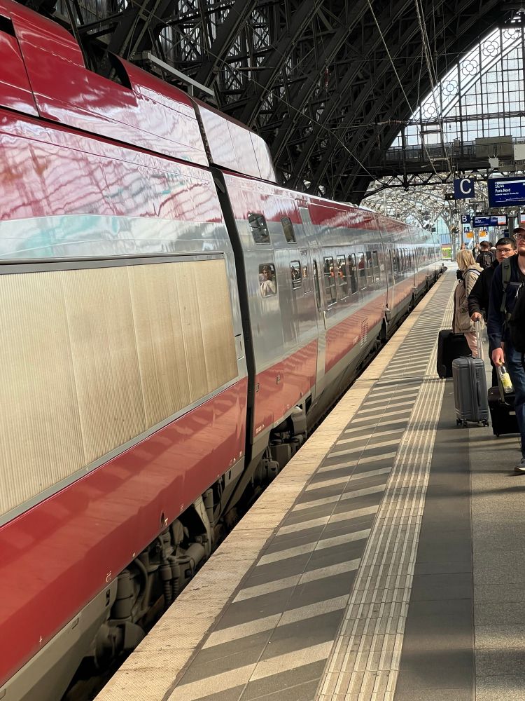 Eurostar anländer till perrongen i Köln. Perrongen är halvfull med väntande resenärer.
