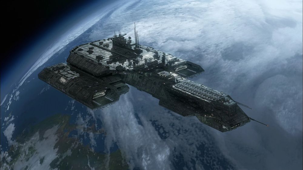 The Daedalus from Stargate: SG-1 and Stargate: Atlantis. It is a human-made deep-space carrier ship, with two large landing bays flanking the long main structure of the ship. The command deck and communication towers are visible along the top of the ship. It is orbiting a lush green and blue planet, possibly Earth.