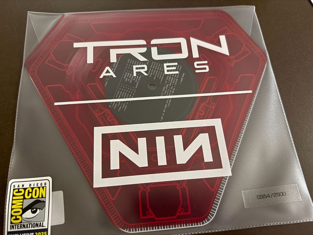 A picture of NIN's Tron: Ares single on vinyl. The vinyl has a triangular shape and is red.