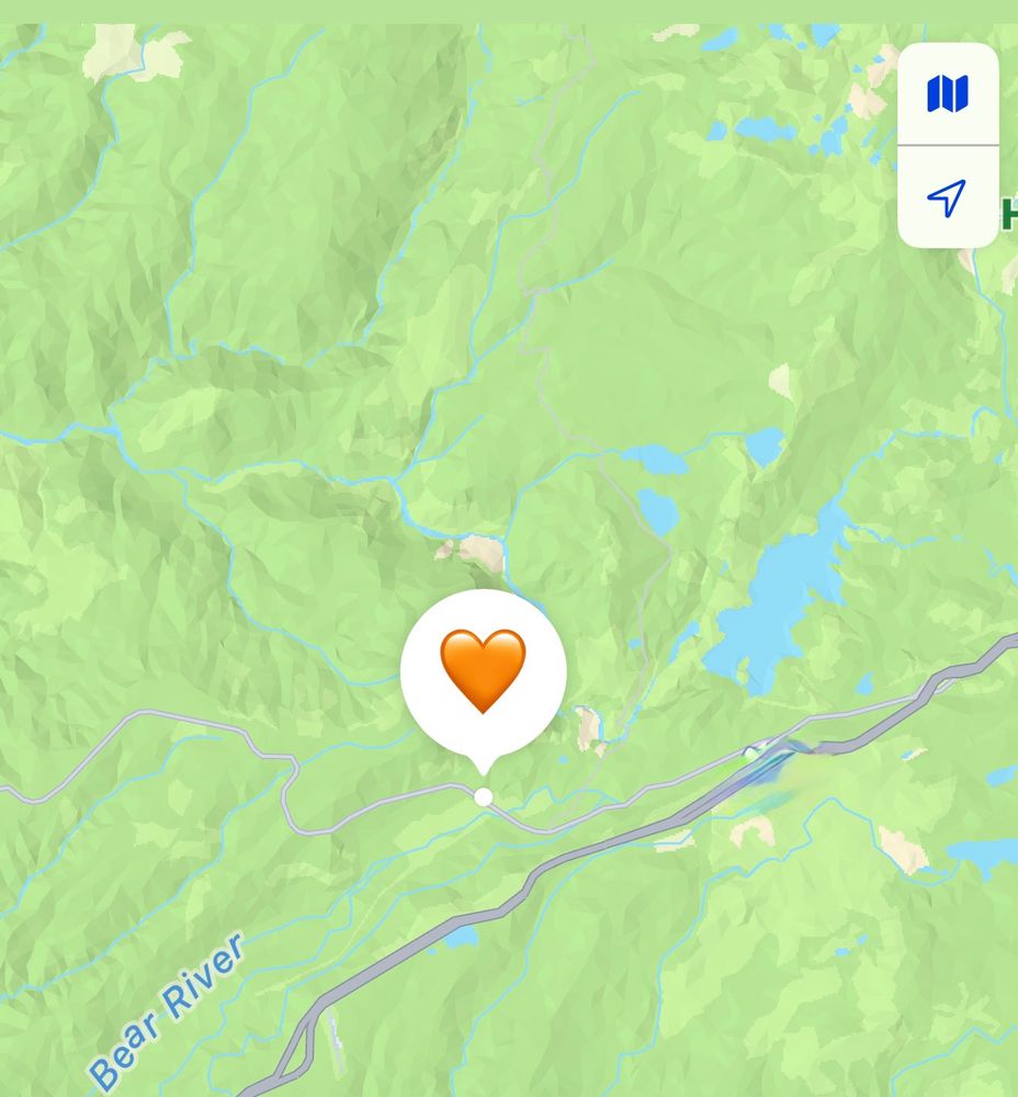 A topographical map showing mountains, rivers and a lake, with a large orange heart indicating an AirTag located somewhere, a distance off a forest road.