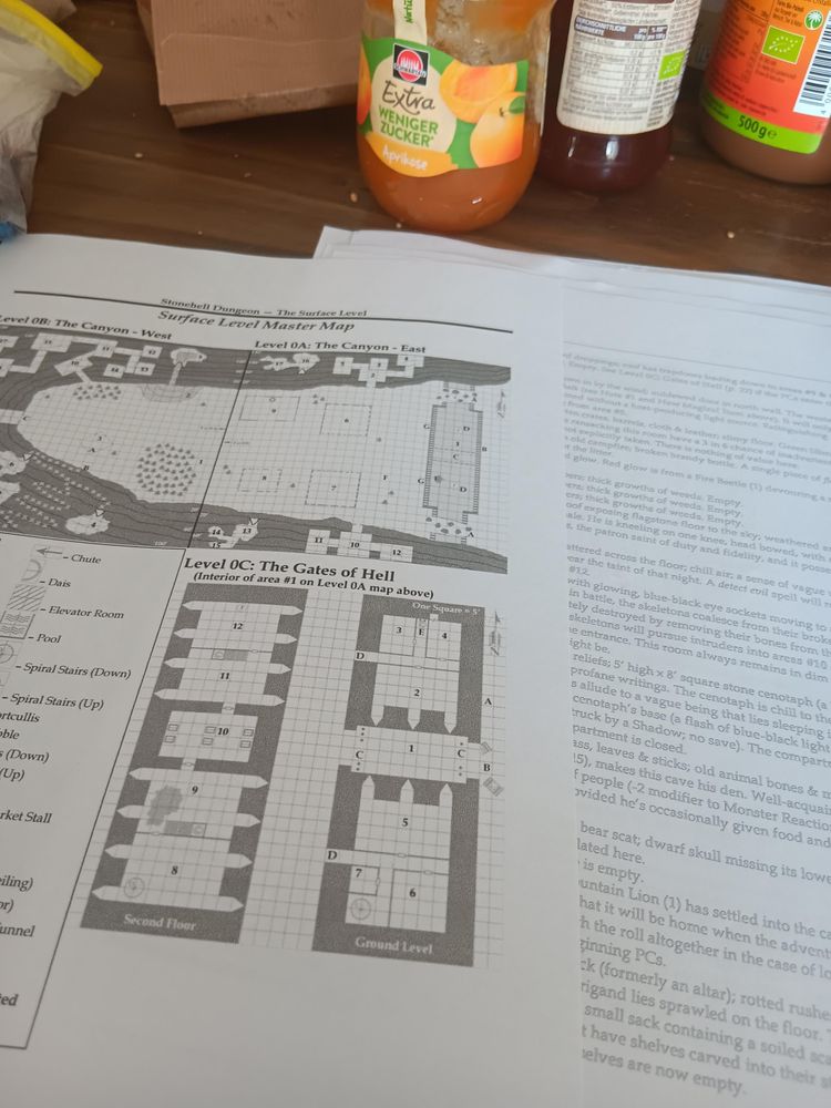Eine Dungeonkarte mit der Beschriftung "Gates of Hell". Landkarte und einige Räume. Halb verdeckt die Legende auf einem Extrablatt. Im Hintergrund Marmeladengläser eines Frühstückstischs.