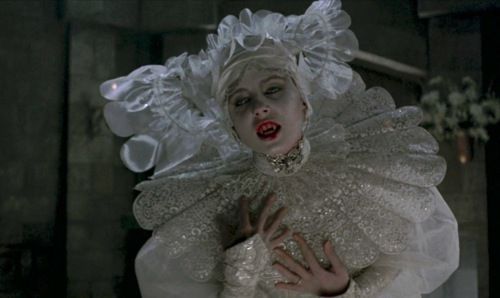 A pale-faced vampire woman in a white dress.