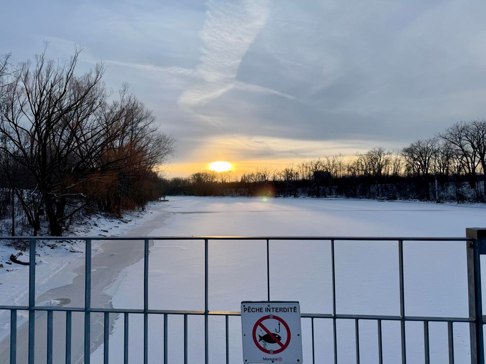 Panneau sur une barrière : pêche interdite avec la rivière gelée sous le pont. 