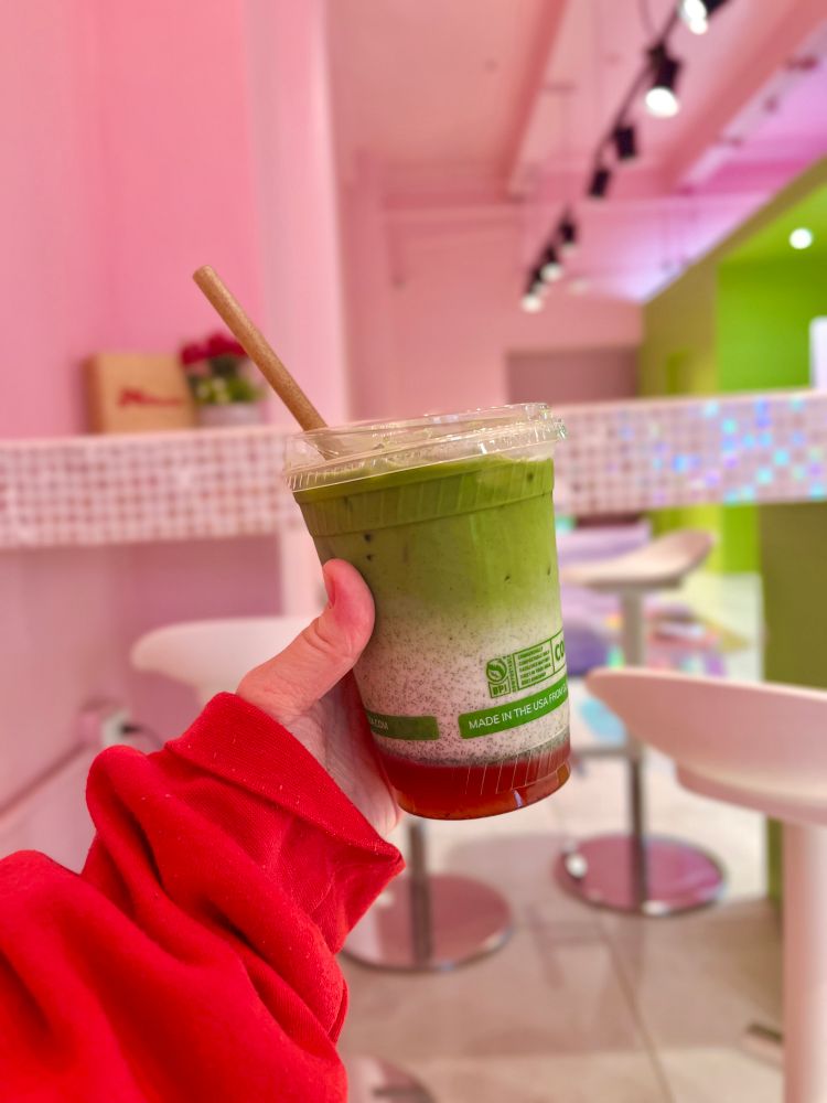 Ashley holds up a plastic cup filled with a beautiful ombré of bright green matcha, oat milk and strawberry purée from Matcha Muchacha in San Juan. 