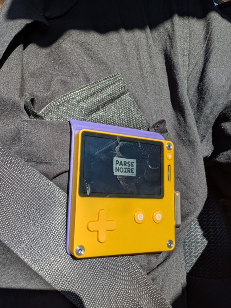 a playdate console hanging from the chest pocket by its case, with parse's logo on the screen