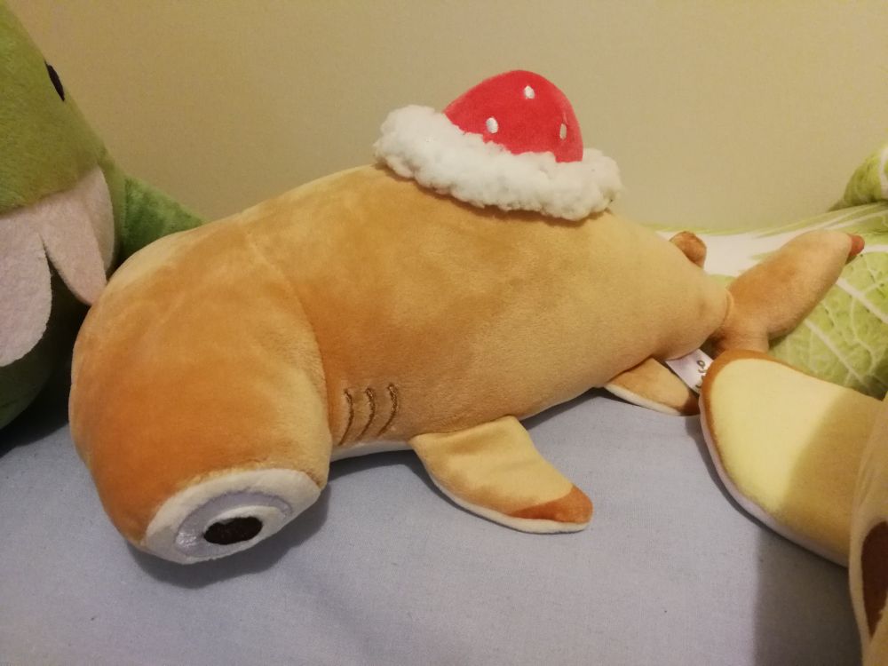 Side view of Rolf the Roll Cake Shark Plush by AfternoonFika, a golden hammerhead shark with a strawberry and cream where the dorsal fin would be