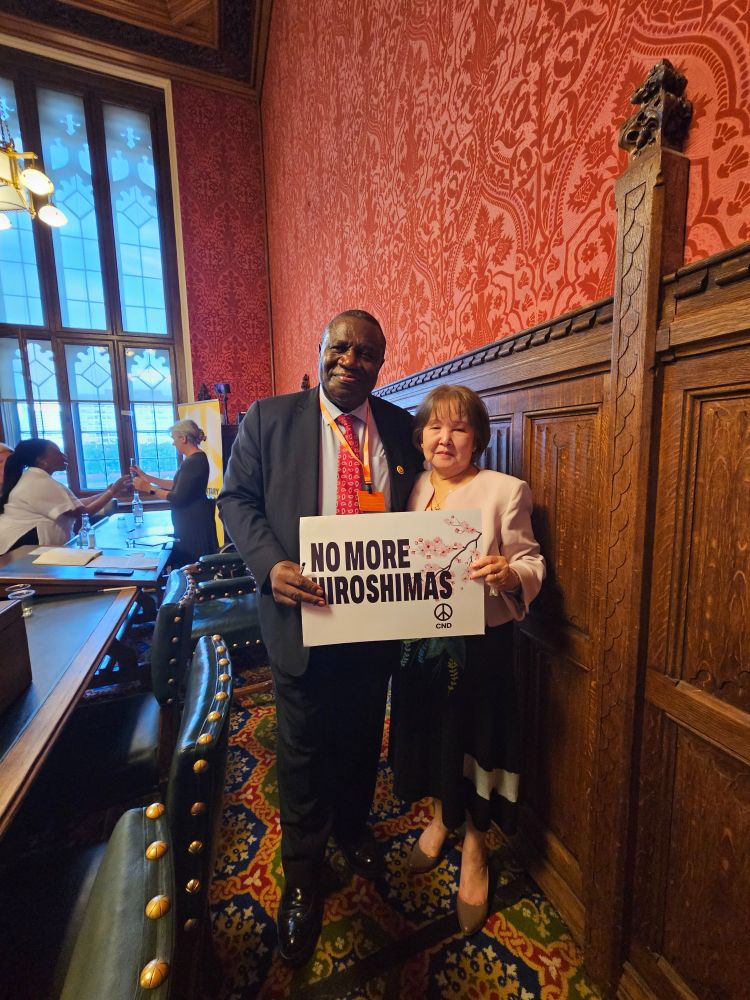 His Excellency Jeremiah Nyamane Mamabolo, South African High Commissioner to the UK, and Kyoko Gibson hold a CND placard reading "No more Hiroshimas"
