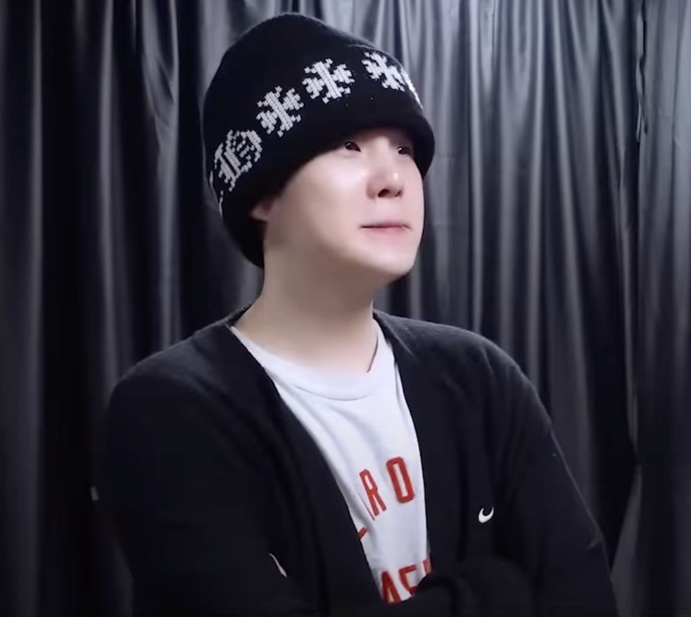 Suga of BTS looking like an anxious lil dumpling, biting his lip in his tshirt and cardigan and chrome hearts beanie backstage before Hope on the Stage The Final, from the episode released on 7.22.25