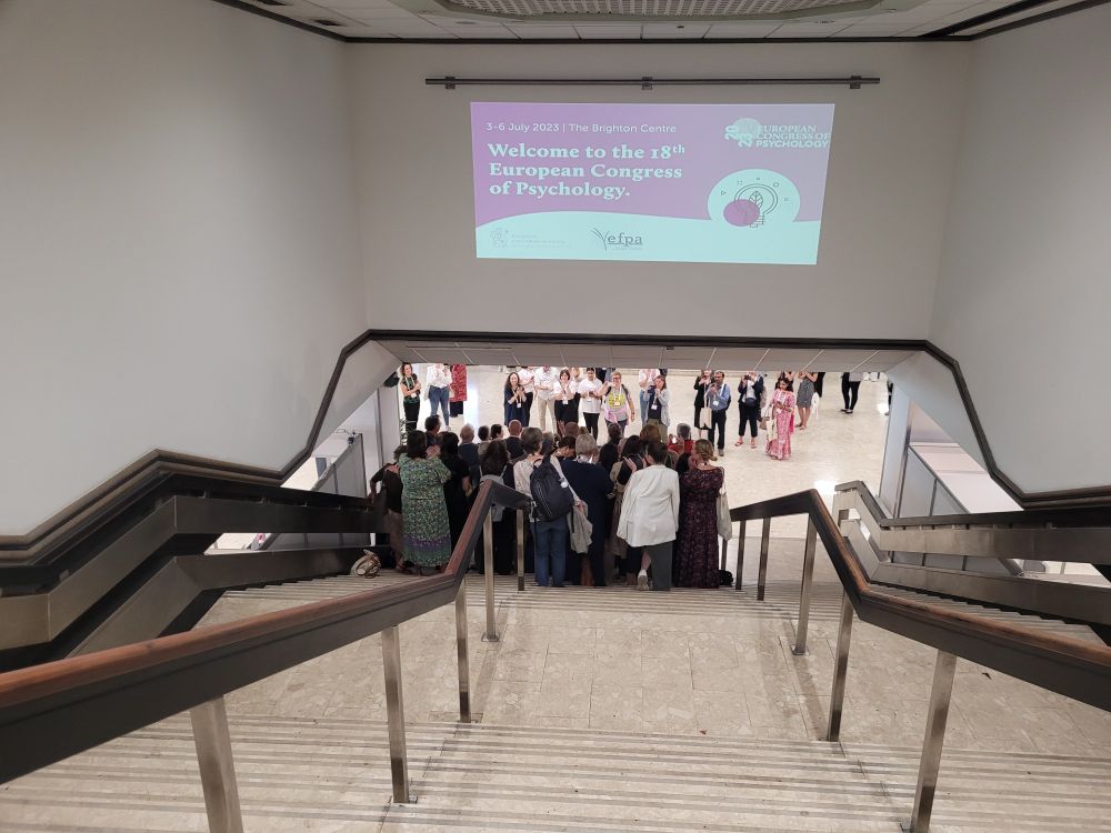 A staircase at a conference venue with a group of people gathered at the bottom.